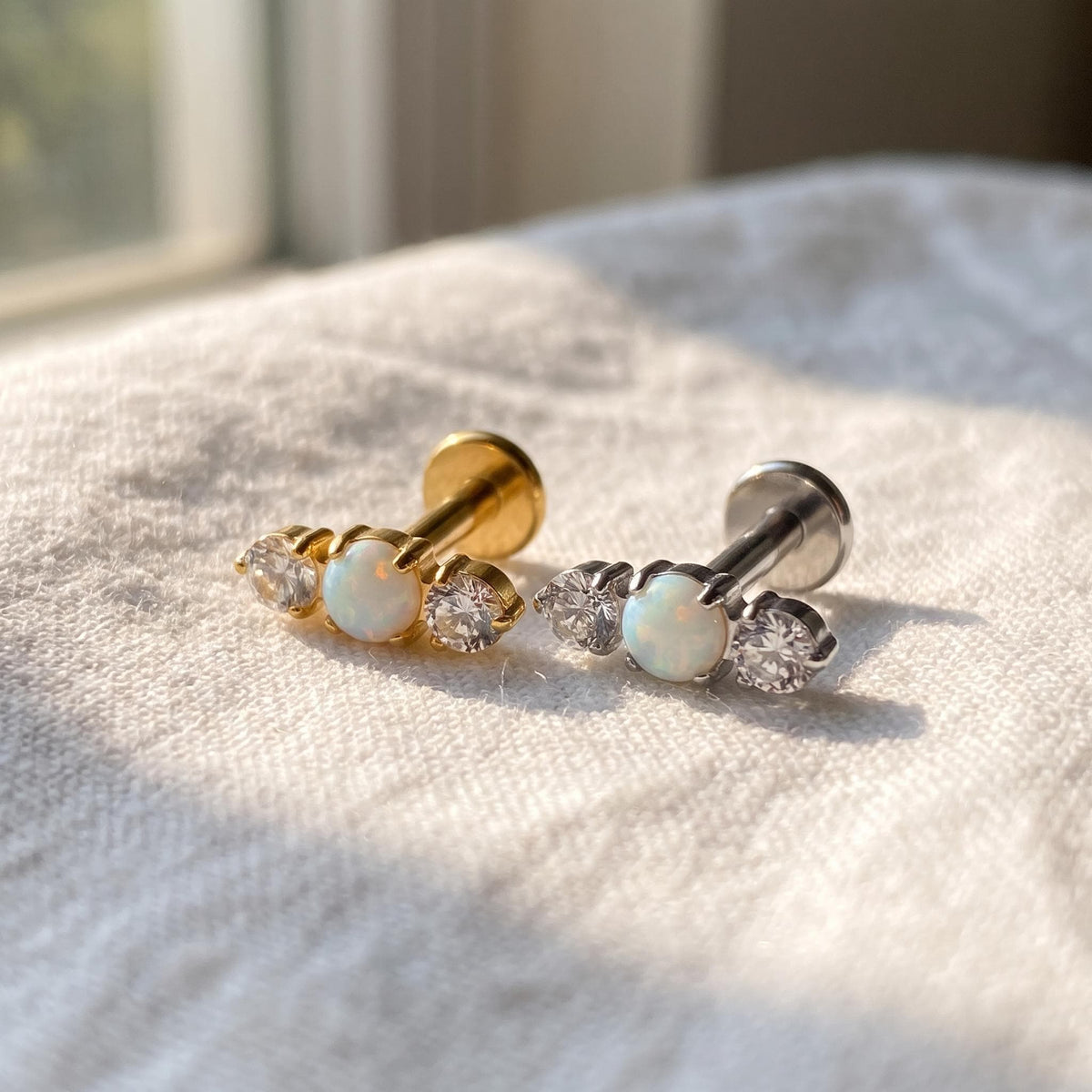Close-up of the three white opals on the titanium flat-back stud, showing the finish detail