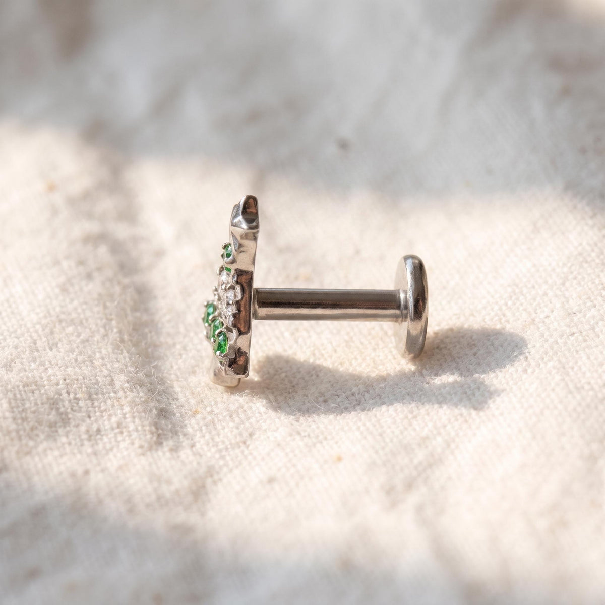 Styled shot of the titanium CZ (cubic zirconia) flat-back stud shown for helix and tragus piercings