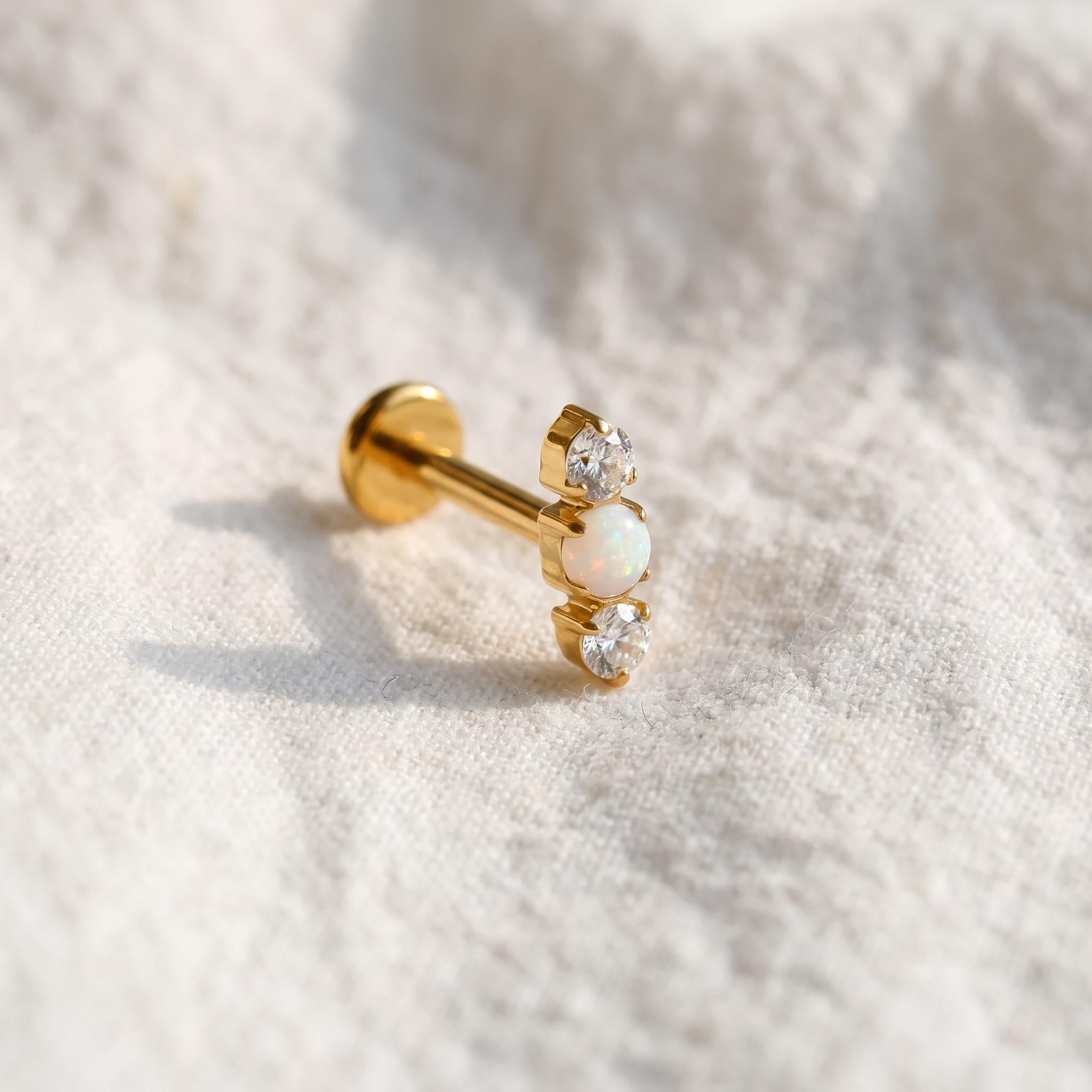 Styled shot of the titanium triple opal stud shown for helix and tragus piercings