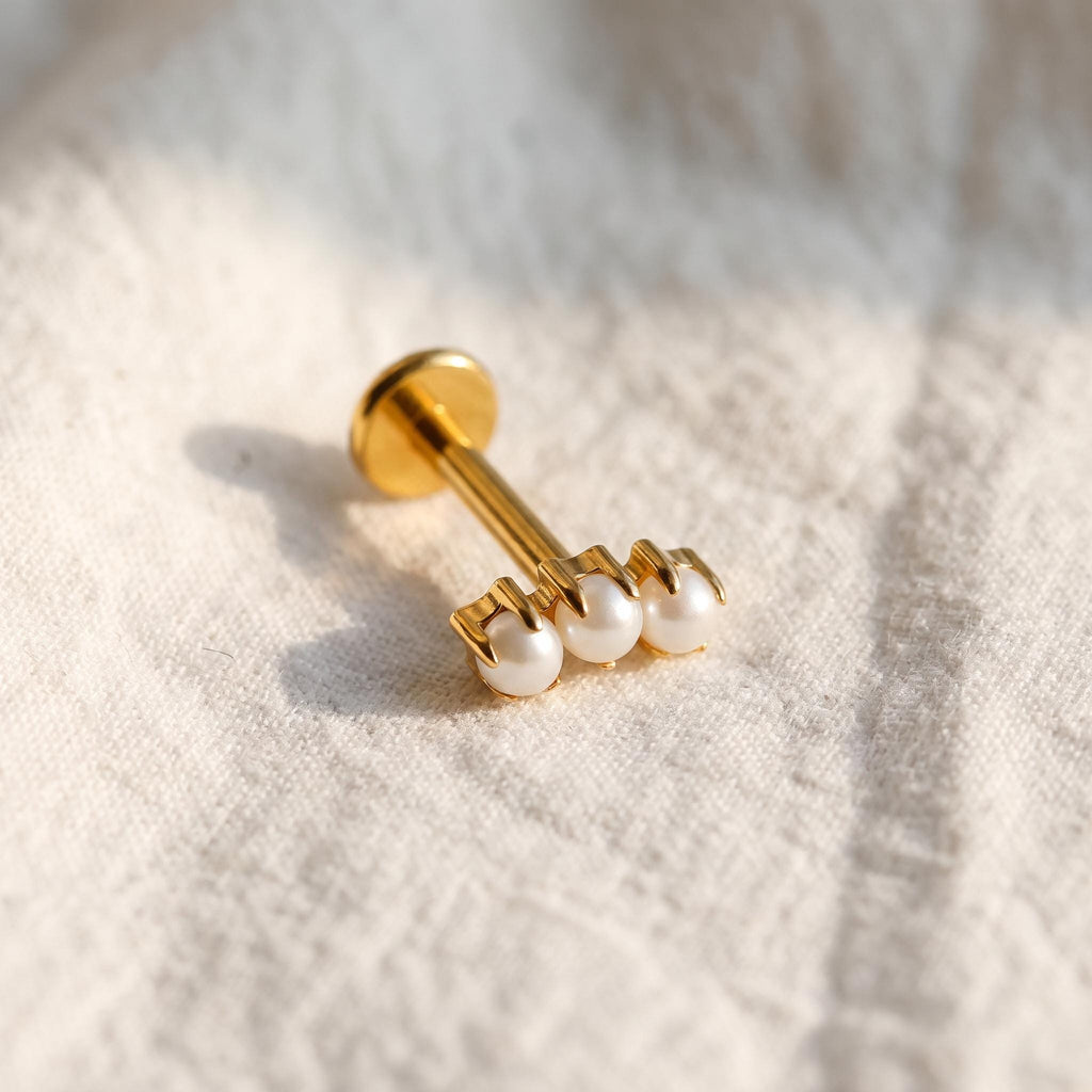 Styled shot of the titanium triple pearl stud shown for helix and tragus piercings