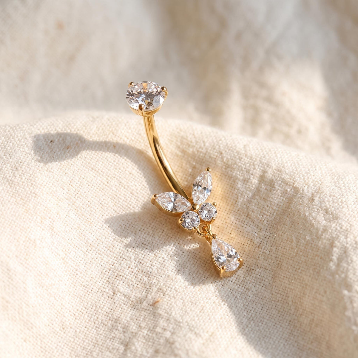 Close-up of the butterfly charm and CZ teardrop on the titanium navel barbell, showing the finish detail
